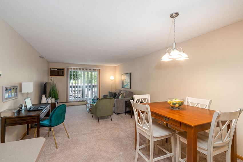 Living room with dining table, couches, and chairs, and a sliding glass door