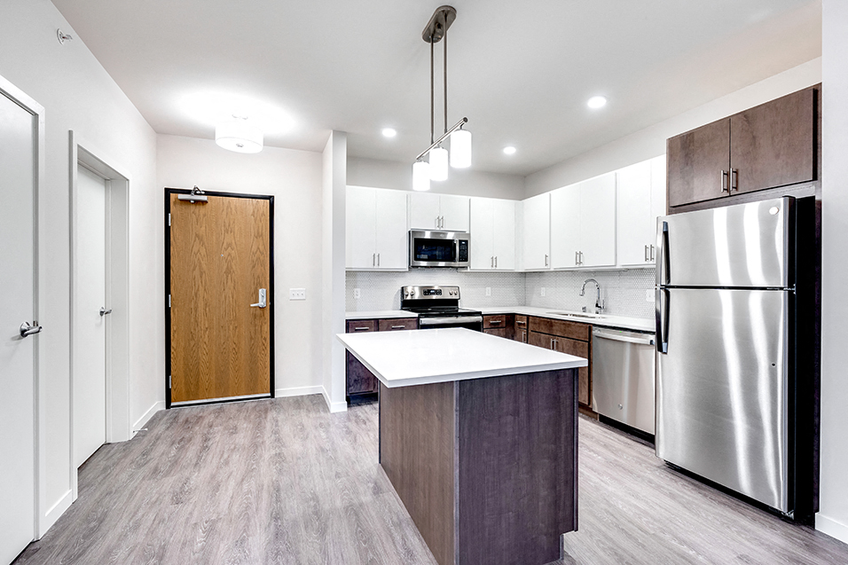 brightly lit apartment entryway and kitchen with island
