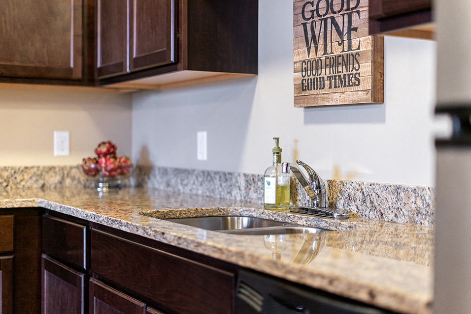 A kitchen counter, a sink, and a sign that says "Good Wine, Good Friends, Good Times"