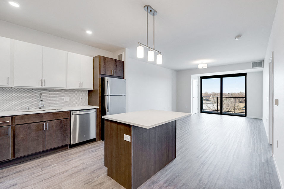 kitchen overlooking empty living room and sliding glass door leading to balcony