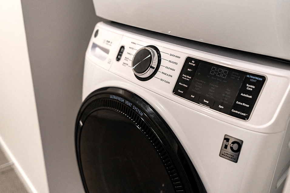 modern, white laundry washing machine with black door and knobs