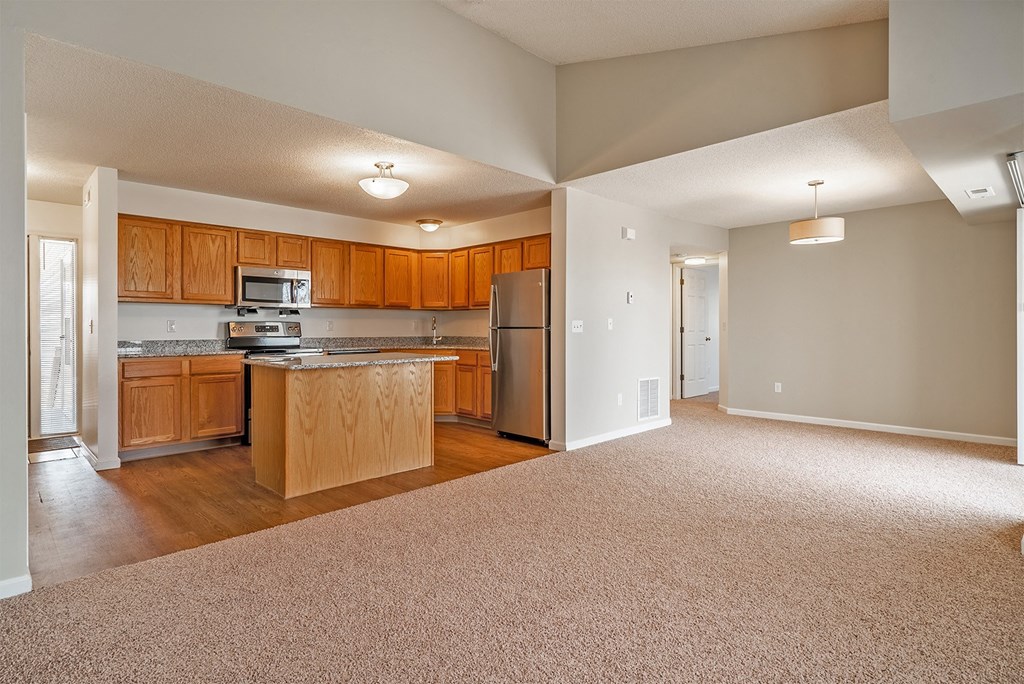 an empty kitchen with wooden cabinets and a stainless steel refrigerator