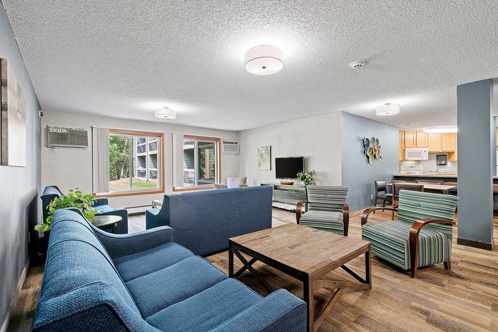 a living room with blue couches and chairs and a wooden coffee table