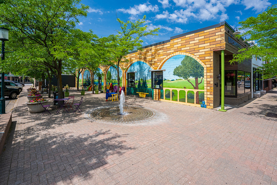 Exterior of a bar with a mural of trees and brick painted on the side