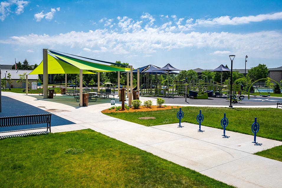 Outdoor playground with green and blue awnings and a walking path