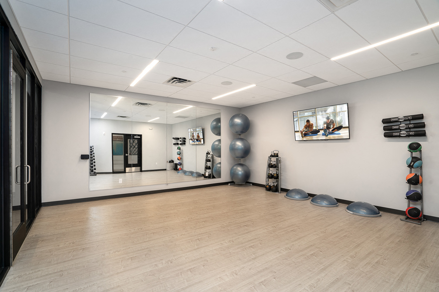 Yoga studio with mirrors, yoga balls, mats, and a TV