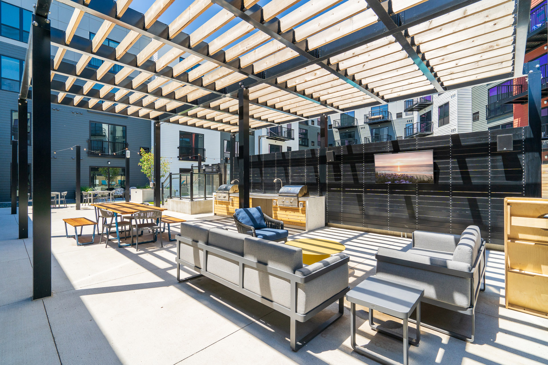 Outdoor community space with grills, sofas, and TV