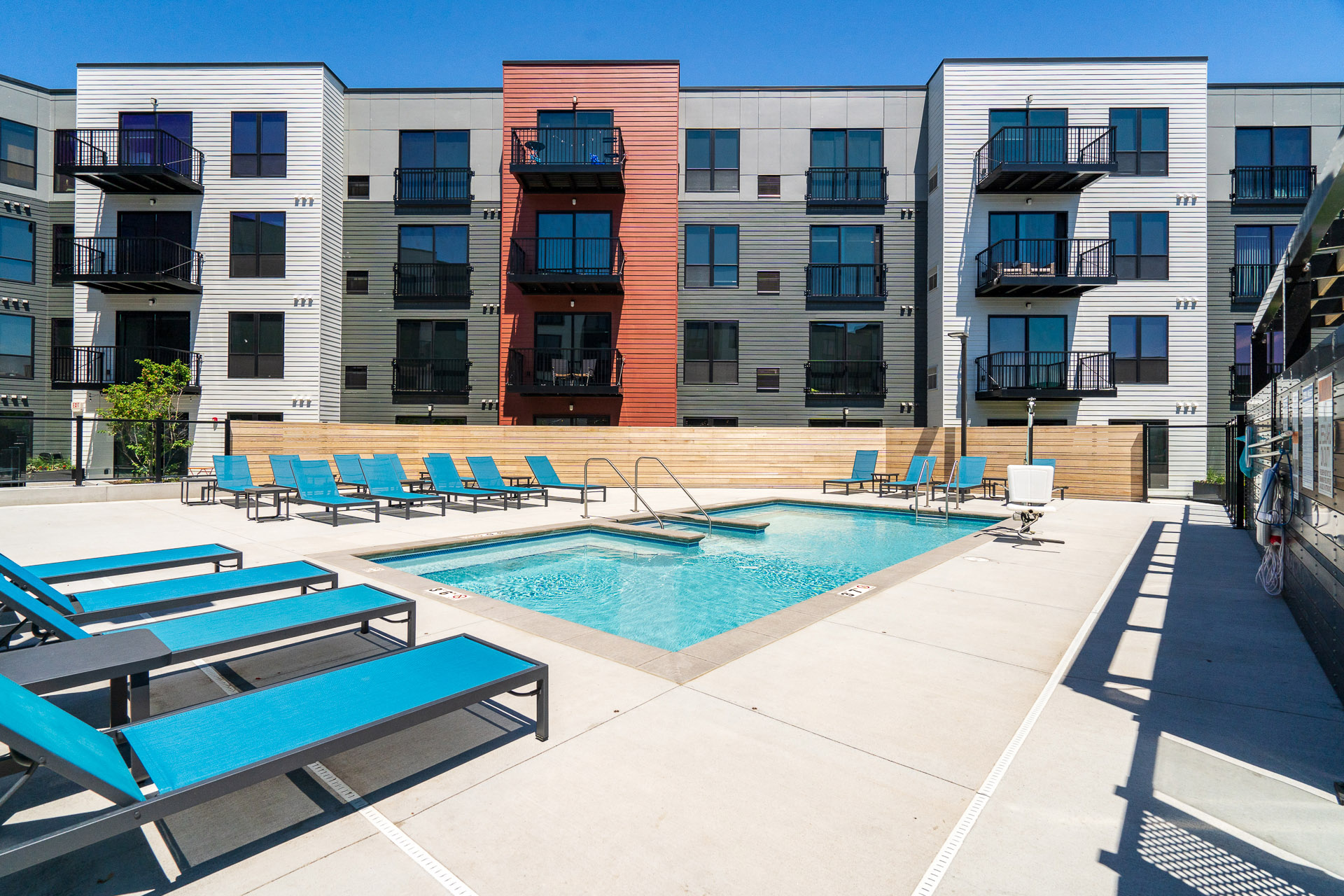 Community outdoor pool surrounded by blue pool chairs
