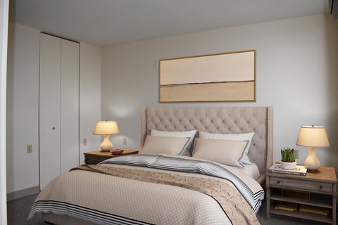 A bedroom with a large bed and two lamps on side tables.