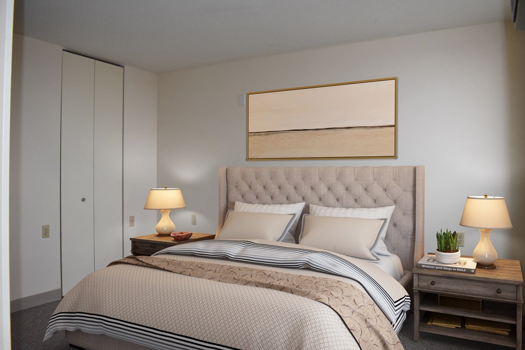 A bedroom with a large bed and two lamps on side tables.