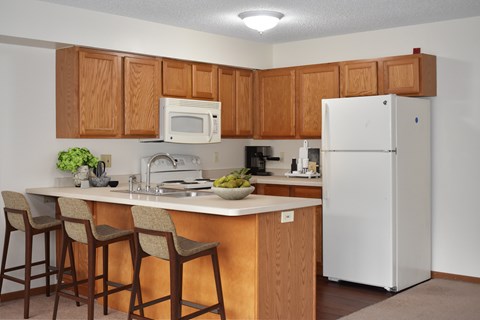 A kitchen with a white refrigerator and wooden cabinets.
