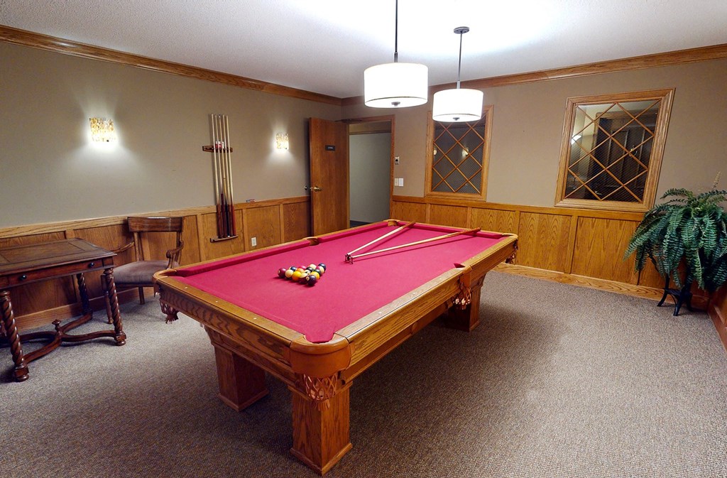 a red pool table in a room with a wooden table and chairs