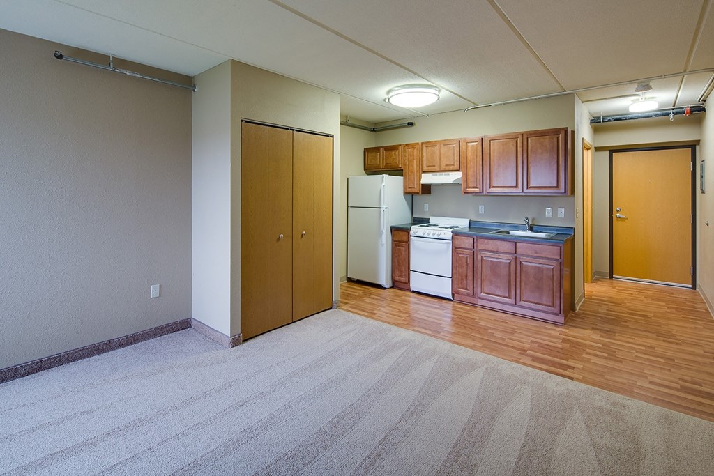 an empty living room and kitchen with wood flooring