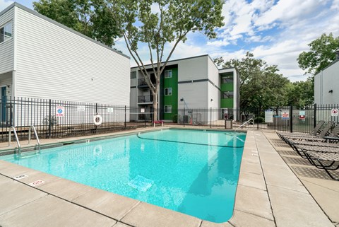 A swimming pool in front of a building with a green door.