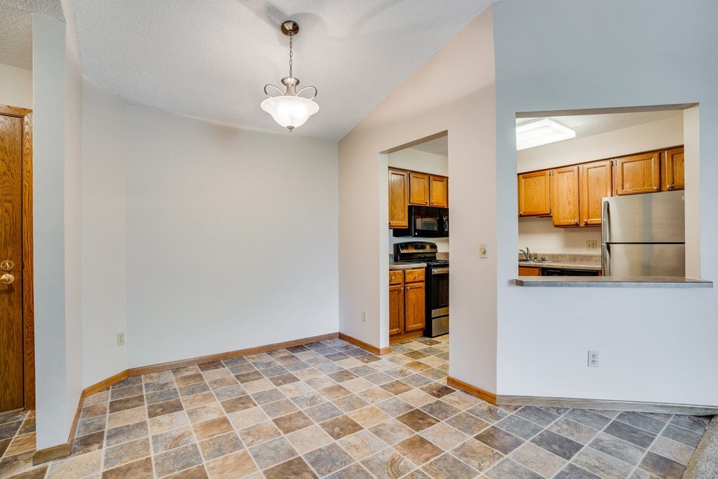an empty living room with a kitchen in the background