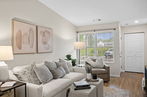 A living room with a white couch, a coffee table, and two framed artworks on the wall.