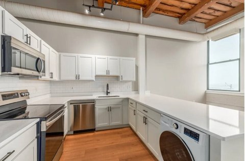 A modern kitchen with white cabinets and stainless steel appliances.