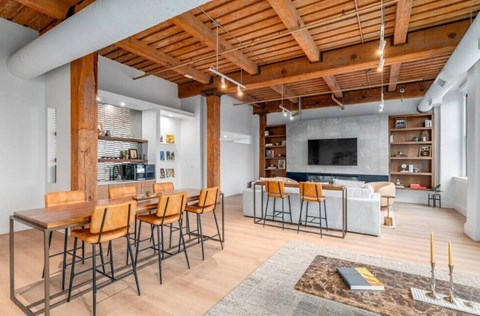 A modern living room with a wooden ceiling and a long table with chairs.