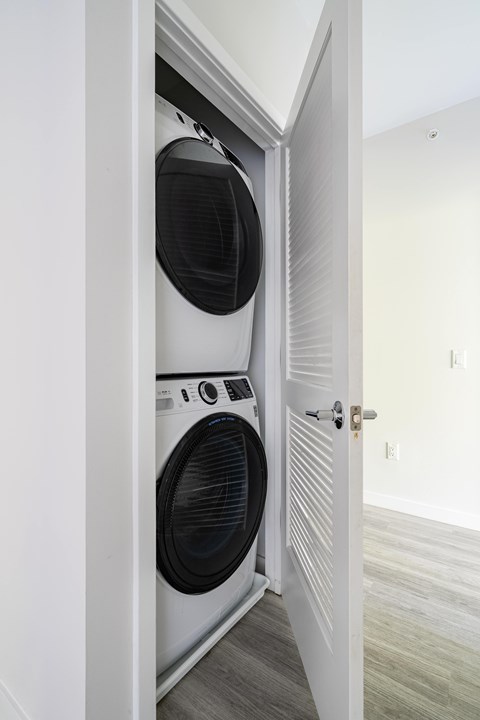 A white door is open to reveal a black washing machine.