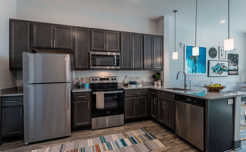 A modern kitchen with dark wood cabinets and stainless steel appliances.