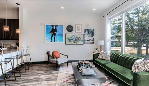 A living room with a green couch and a painting of a man on the wall.