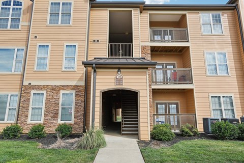 A multi-story apartment building with a covered walkway leading to the entrance.