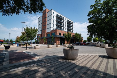 A large building with a red brick facade is surrounded by trees and planters.