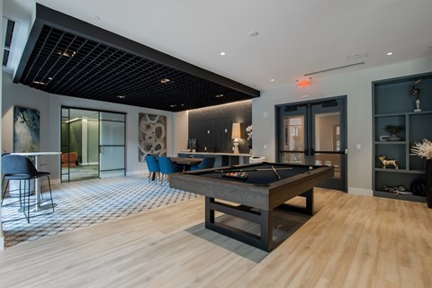 A room with a pool table and a bar area.