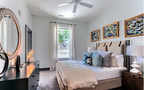 A bedroom with a large bed, a dresser, and a ceiling fan.