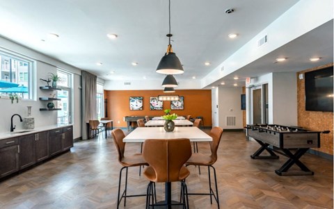 A dining room with a pool table and a kitchen area.
