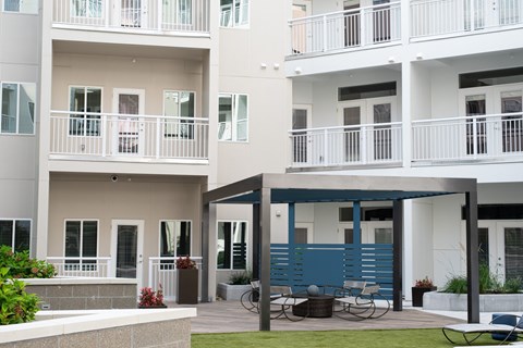 A white apartment building with a blue awning and a patio with a table and chairs.