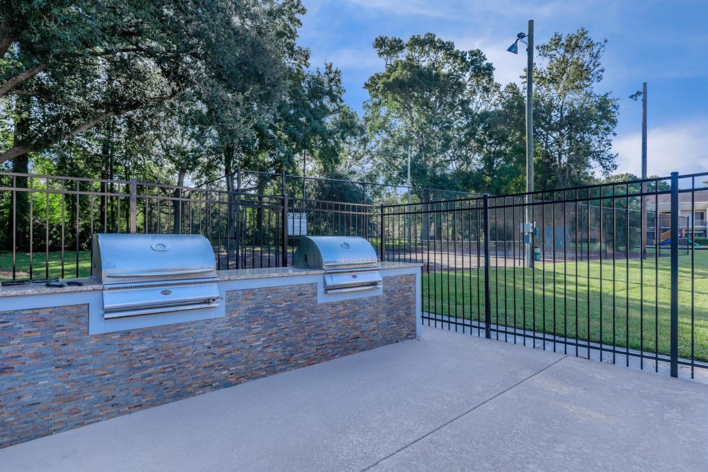 a patio with two bbq pits and a black fence at Sawgrass Apartments, Charleston, SC