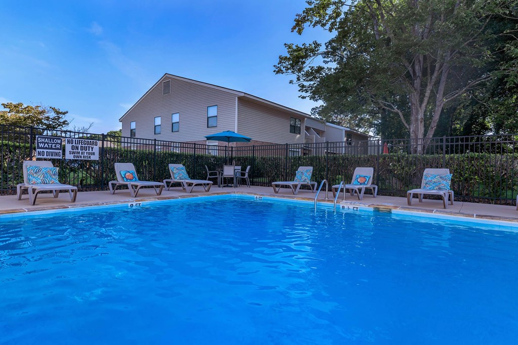 a swimming pool with chairs and a house in the background a swimming pool with chairs and a house in the background at Sawgrass Apartments, South Carolina, 29412
