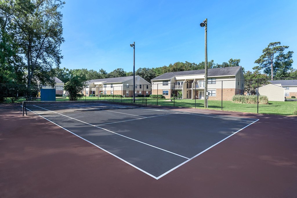 an empty tennis court with apartments in the background at Sawgrass Apartments, Charleston, 29412
