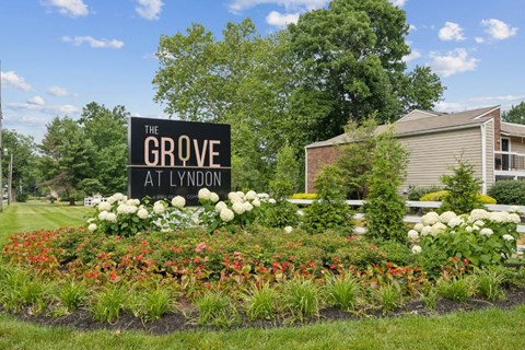 the grove apartments sign in front of flowers and plants