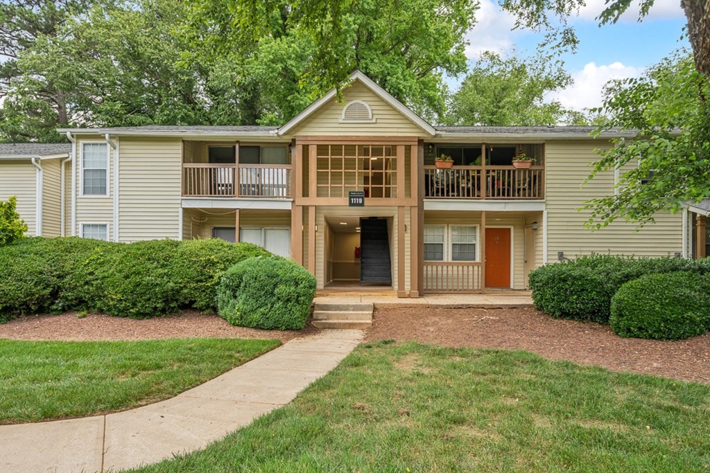 a yellow house with a sidewalk in front of a yard