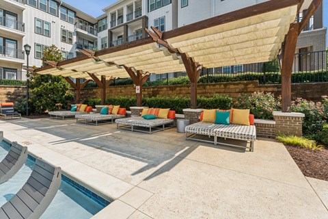 a group of lounge chairs under a large canopy next to a pool at Beckett Farms Apartments, PRG Real Estate Management, Fort Mill, 29715