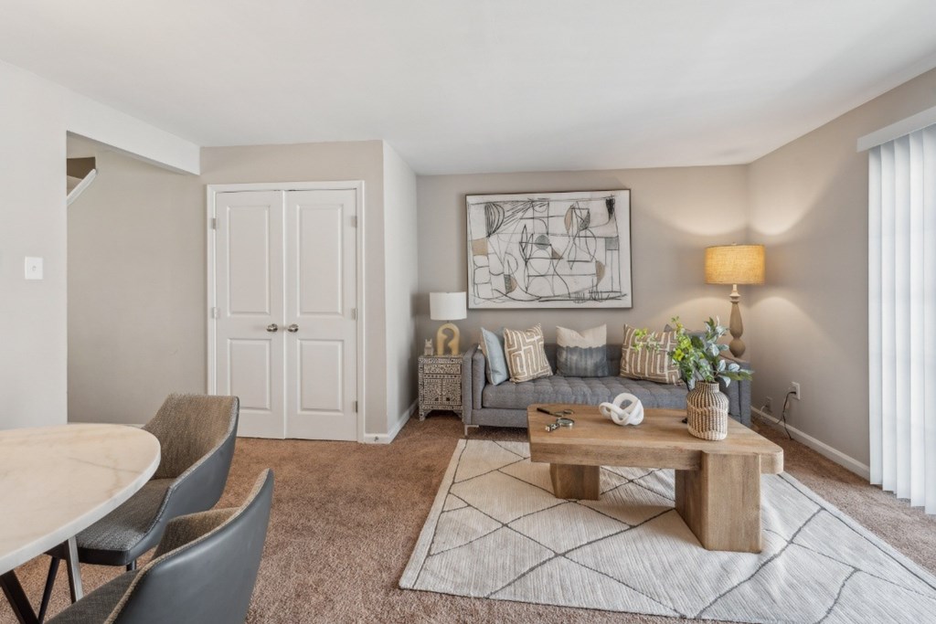 A living room with a grey sofa, a wooden coffee table, and a grey rug at Staples Mill Townhomes Apartments, Richmond, VA, 23228