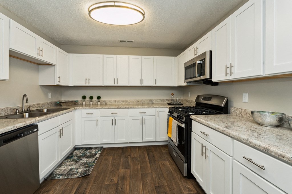 a kitchen with white cabinets and a black stove and microwave at Hyde Park Townhomes, PRG Real Estate Management, Chester, VA