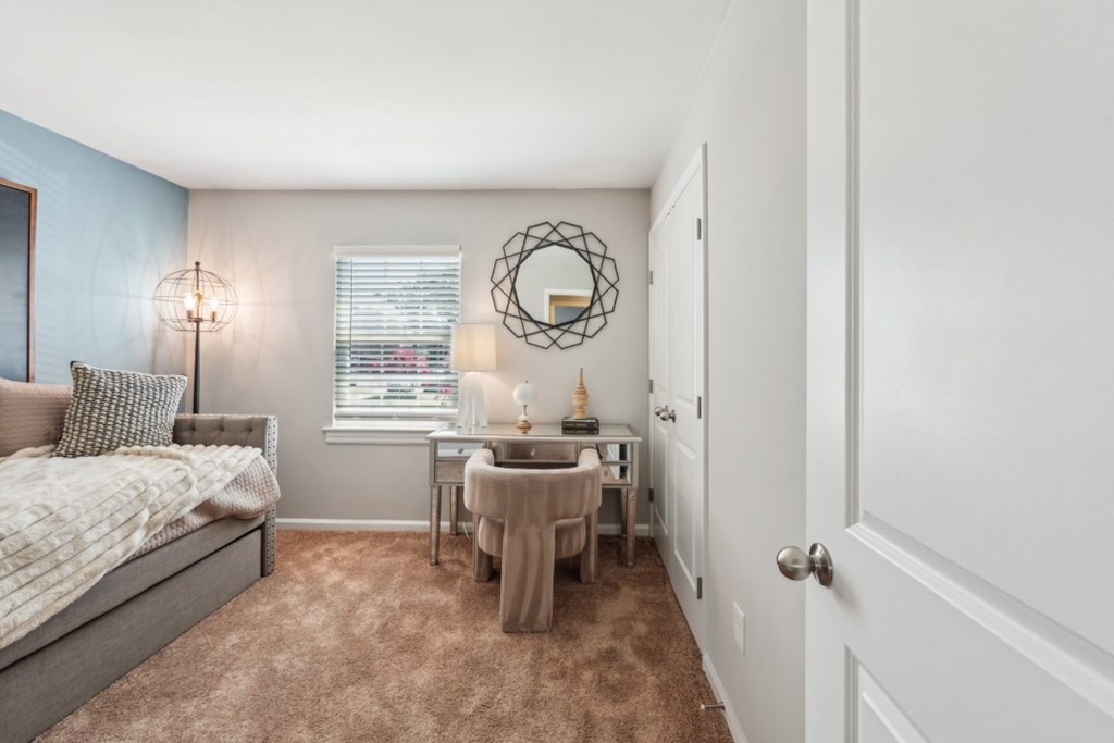 A bedroom with a bed, desk, and chair at Staples Mill Townhomes Apartments, Richmond