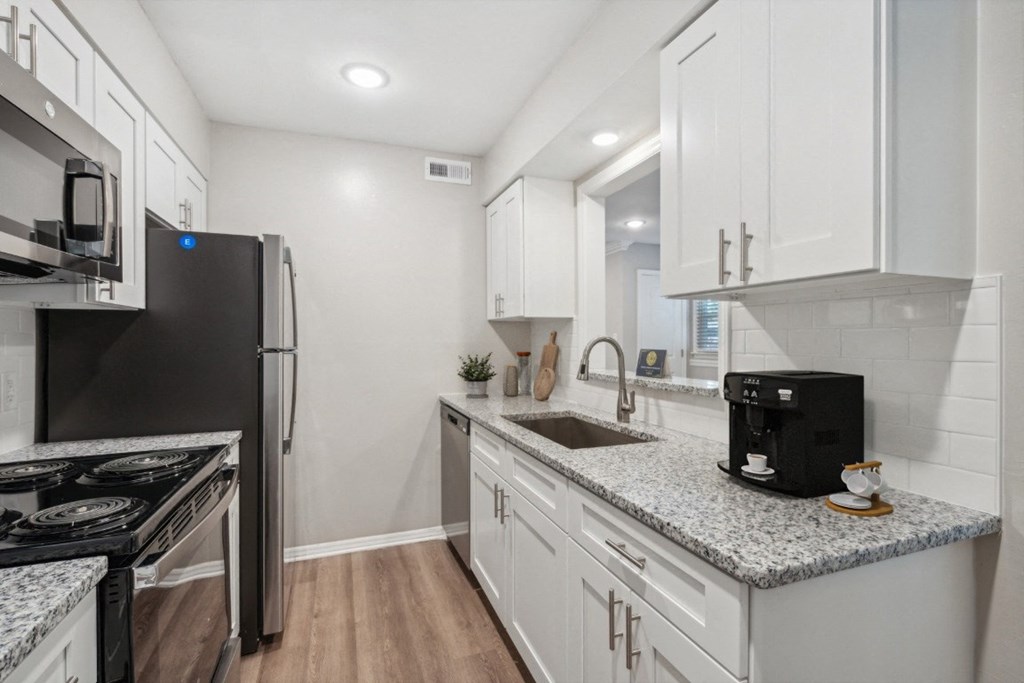 a kitchen with white cabinets and granite counter tops and a stainless steel refrigerator