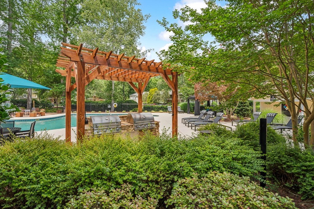 a patio with a wooden pergola and a swimming pool