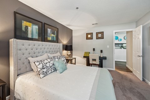 A bedroom with a large bed and a white headboard.