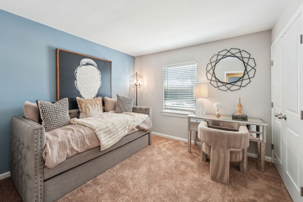 A bedroom with a bed, desk, and chair