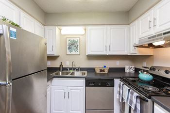 a kitchen with stainless steel appliances and white cabinets at Clarion Crossing Apartments, PRG Real Estate Management, Raleigh