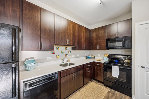 A kitchen with dark wood cabinets and black appliances.