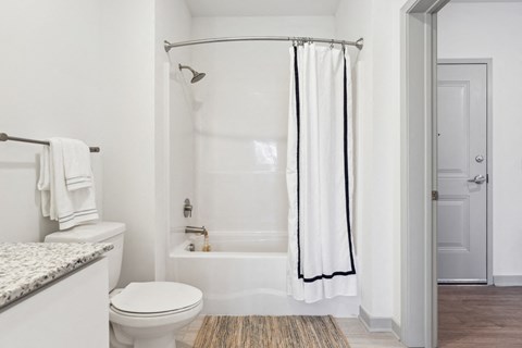 a bathroom with a white toilet next to a white bathtub at The Constellation Apartments, PRG Real Estate, Hampton, Virginia