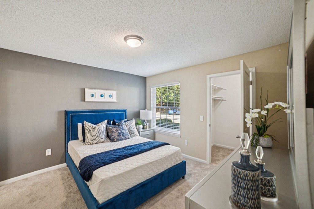A bedroom with a blue headboard and a white bed at Willow Ridge Apartments, North Carolina, 28210