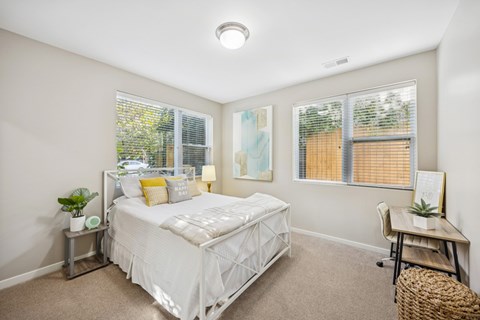 A bedroom with a white bed and a window with blinds.