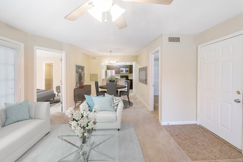 A living room with a white couch and a glass coffee table.